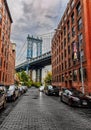 View of Manhattan Bridge with parked cars and brick buildings in the foreground Royalty Free Stock Photo