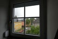 View from mansard window to town street with color houses and cars in rainy day