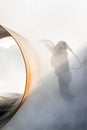 View of the manuel sandblasting to the large pipe. Abrasive blasting more commonly known as sandblasting is the operation.