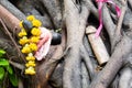 Marigold flowers on phallus shape wooden figure left near trees in Chao Mae Tuptim phallic shrine, Bangkok, Thailand