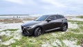 View of a Mazda CX-3 car parked at the beach under the cloudy sky