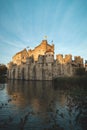 View of the medieval Gravensteen Castle and its reflection in the canal during sunset in the centre of Ghent, Belgium. Historical