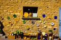 View on mediterranean colorful painted pottery plates hanging on ochre natural stone wall in natural sun light Royalty Free Stock Photo