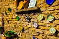 View on mediterranean colorful painted pottery plates hanging on ochre natural stone wall in natural sun light Royalty Free Stock Photo