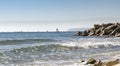 View of the Mediterranean Sea, waves. In the background are ships and sailboats. sunny day. large stones on the shore