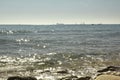 View of the Mediterranean Sea, waves. In the background are ships and sailboats. sunny day. large stones on the shore