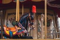 View of a Merry go round carousel black horse with red feathers on its head