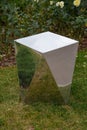 A view of a metal mirror cabinet with a beautiful reflection of green grass