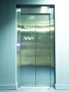 View of the metal shiny elevator doors with a burning bright button near it
