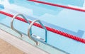 The view of metallic ladder of swimming pool with marked lanes. Royalty Free Stock Photo