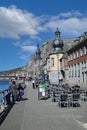 View on meuse riverside promenade with traditional houses, church, rock wall against blue sky, fluffy clouds