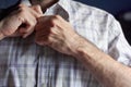 View of midsection of young man`s body, hands buttoning striped shirt