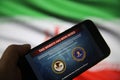 View on mobile phone screen with FBI notification this website has been seized, blurred iran flag background