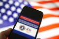 View on mobile phone screen with FBI notification this website has been seized, blurred us flag background