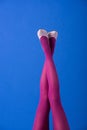 View of model in purple tights and shoes with crossed legs on blue Royalty Free Stock Photo