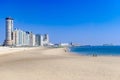 View of a modern coastal city or town and its beach. Big cargo ships in the sea. Summer concept. Vacation.