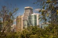 View of Modern high buildings among green trees space in nature against blue sky with clouds at afternoon Royalty Free Stock Photo