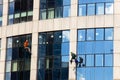 View on modern skyscrape, workers on the ropes cleaning windows