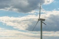 view of a modern windmill against a blue sky. The white blades of the wind turbine close up. Renewable energy source. Production