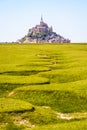 The bed of a dried-up stream snaking in the salt meadow opposite the Mont Saint-Michel tidal island in Normandy, France Royalty Free Stock Photo