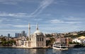 View of a moored cruise tour boat on Bosphorus, historical Ortakoy mosque in Istanbul. It is a sunny summer day.