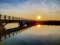 View of the morning sun over the bridge with reflections in the calm water Royalty Free Stock Photo