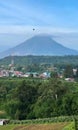 view of Mount Sinabung covered in clouds with residential areas surrounding it Royalty Free Stock Photo