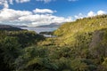 View on Mount Tarawera over Lake Tarawera with lush forest in foreground and cloudy blue sky, Rotorua