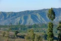 View of mountain ridges and sloping hills with trees under a clear blue sky