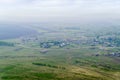 View from the mountain to the Russian village with a church and fields through a foggy haze Royalty Free Stock Photo