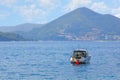 View of the mountains covered with forest and sky with clouds. A coastal city with orange roofs. Yacht at sea