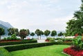 View of the mountains, the lake and the embankment of the city with trimmed trees, shrubs, lawn and flower beds.