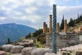 View of mountainside site of ancient Delphi Greece with twisted column in front of Temple of Apollo with a treasury down the hill