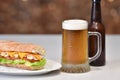 View of a mug of beer next to a delicious looking sub sandwich with meat and vegetables Royalty Free Stock Photo