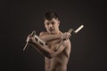 Studio shot of a muscled man in single combat weapon pose with nunchaku on a black background Royalty Free Stock Photo