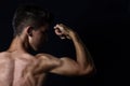 View of muscular teenager flexing biceps in front black backgrou