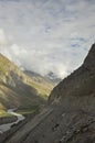 View of narrow cliffside mountain road with flowing a river in between dry mountains in Manali-Leh highway Royalty Free Stock Photo