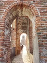 View of narrow cobbled path, curving from ancient castle walls with orange brick walls all around, through brick arches. High Royalty Free Stock Photo