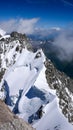 Narrow and exposed summit ridge with a giant wave cornice on the way to the top of a peak in the Alps