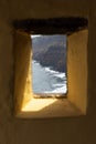View through narrow stone embrasure window framing distant rugged sea cliffs and rolling waves along the Atlantic coast Royalty Free Stock Photo