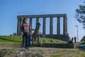 View of National Monument of Scotland, on Calton Hill in Edinburgh, cannon sculpture and people, grass around and people enjoying