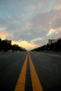 View of a new asphalt road with yellow markings closeup and sunset sky in the background. Royalty Free Stock Photo