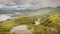 A view from the new and easier path on the Storr. Glamaig mountain in the distance shrouded in clouds. two tourists enjoying the