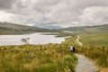 A view from the new and easier path on the Storr. Glamaig mountain in the distance shrouded in clouds. two tourists enjoying the