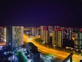 View of the night city from a height. tall houses with panoramic windows and painted facades. next to a busy road for pedestrians