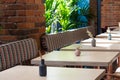 View of a number of empty tables in a cafe on a background of a brick wall and palm trees. Concept interior, business, quarantine