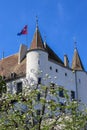 View at Nyon castle with flag waving on the roof through blooming tree