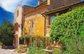 View on ochre natural stone farm house in provence style with lush green garden, blue sky - Roussillon, France Royalty Free Stock Photo