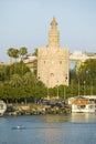 View of the octagonal tower of Torre del Oro makes golden reflection on Canal de Alfonso of Rio Guadalquivir River, Sevilla Spain