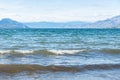 Close-up of waves on Okanagan Lake with view of mountains on sunny day Royalty Free Stock Photo